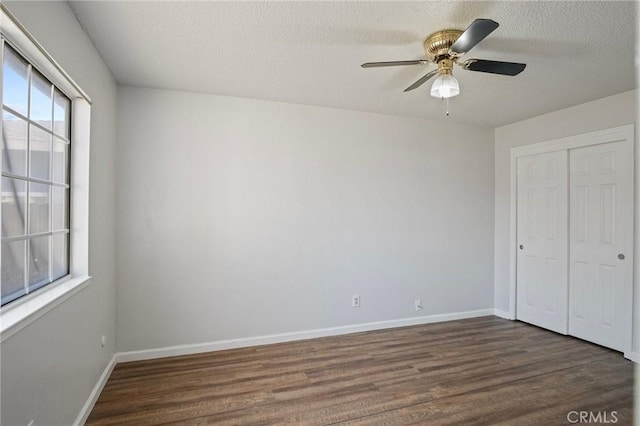 unfurnished bedroom featuring dark hardwood / wood-style floors, a textured ceiling, a closet, and ceiling fan