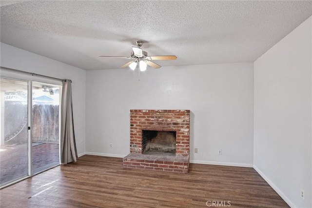 unfurnished living room featuring a brick fireplace, dark wood-type flooring, a textured ceiling, and ceiling fan