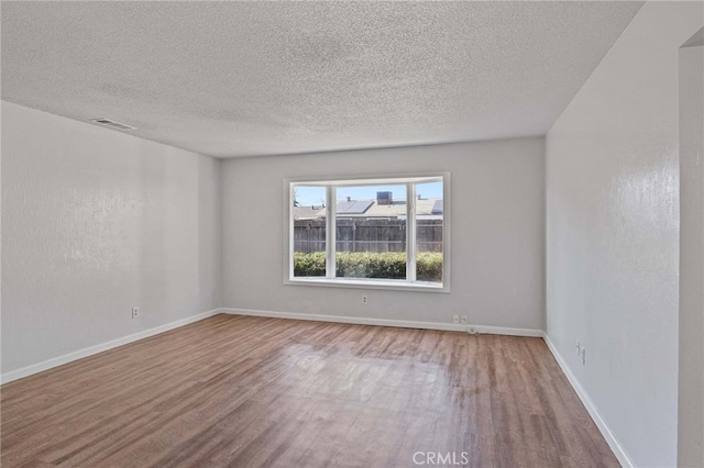 empty room featuring a textured ceiling and light hardwood / wood-style floors