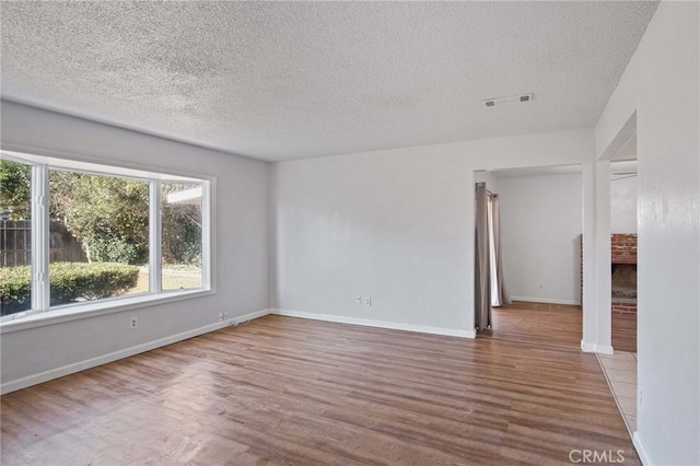 unfurnished room featuring hardwood / wood-style floors, a wealth of natural light, and a textured ceiling