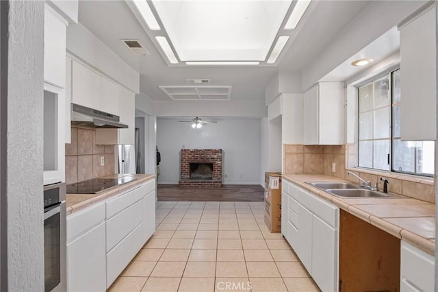 kitchen featuring black electric stovetop, decorative backsplash, oven, and white cabinets