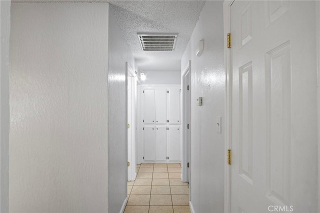 corridor with light tile patterned floors and a textured ceiling