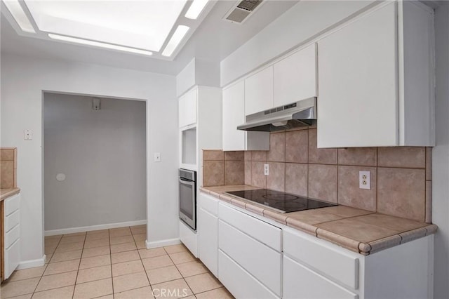 kitchen featuring white cabinetry, stainless steel oven, tile counters, light tile patterned floors, and black electric cooktop