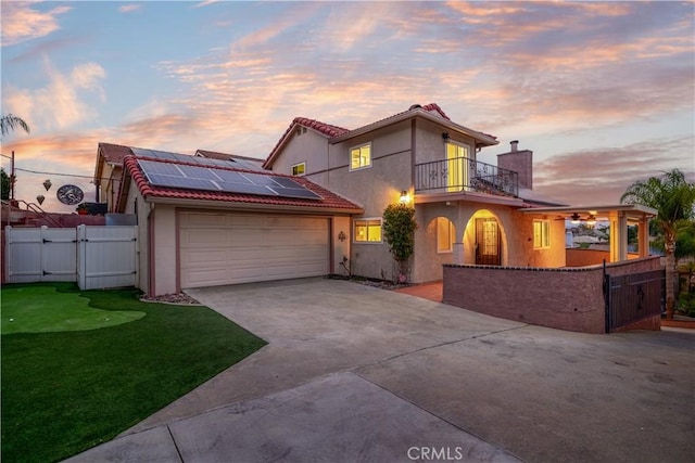 view of front facade with fence, roof mounted solar panels, stucco siding, a balcony, and a gate