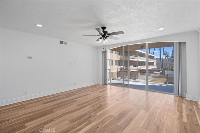 empty room with ceiling fan, a textured ceiling, baseboards, and wood finished floors