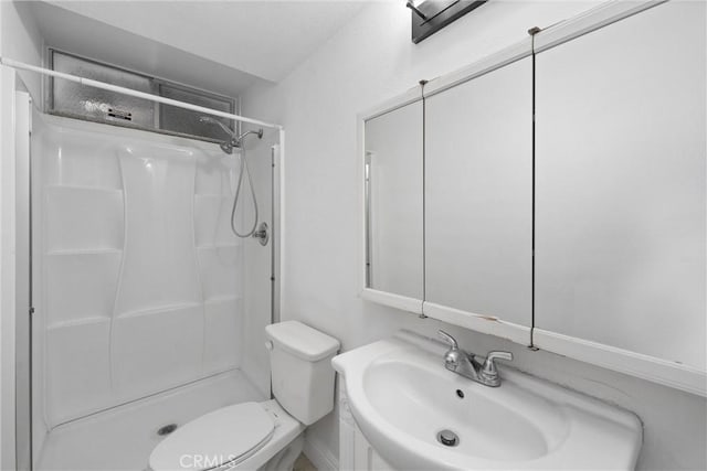 bathroom featuring a sink, a shower stall, and toilet