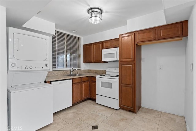 kitchen with white appliances, a sink, stacked washer / drying machine, light countertops, and brown cabinets