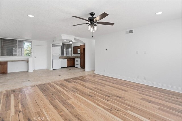 unfurnished living room with ceiling fan, sink, and light hardwood / wood-style flooring