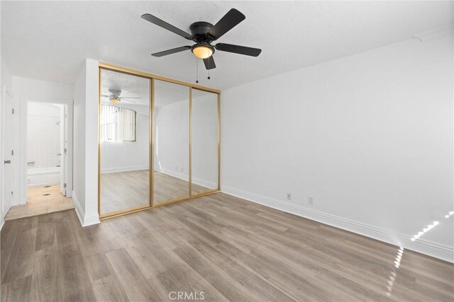 unfurnished bedroom with ceiling fan, hardwood / wood-style floors, and a closet