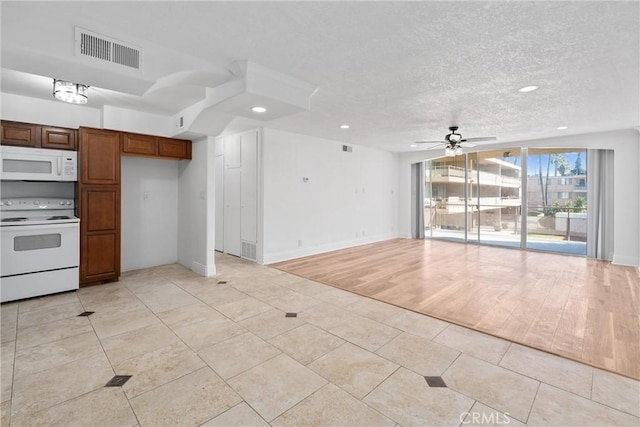 kitchen featuring ceiling fan, a textured ceiling, white appliances, visible vents, and open floor plan