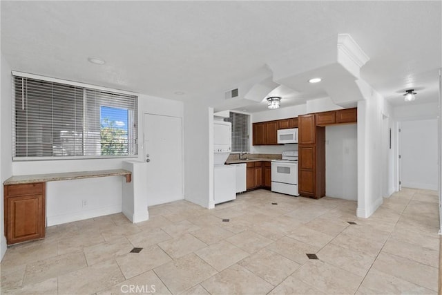 kitchen featuring white appliances, visible vents, baseboards, light countertops, and brown cabinetry