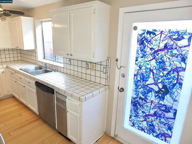 kitchen with dishwasher, tile counters, white cabinetry, and backsplash