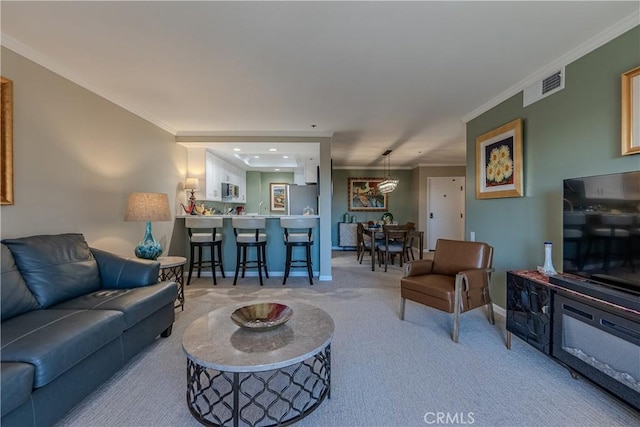 living room featuring light colored carpet, crown molding, and sink