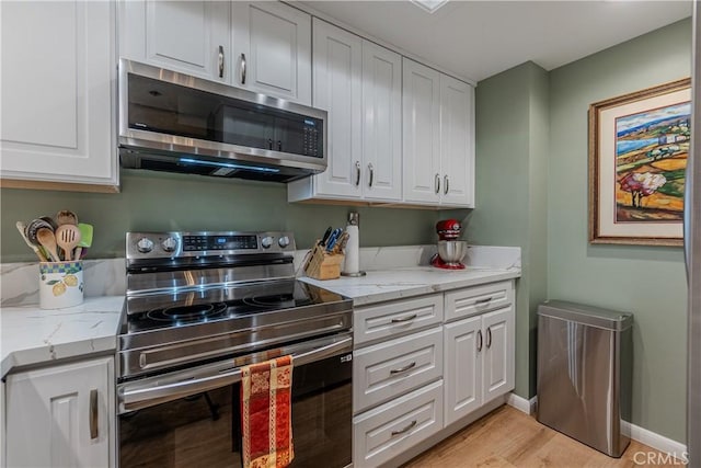 kitchen featuring stainless steel appliances, white cabinetry, light stone countertops, and light hardwood / wood-style flooring