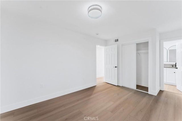 unfurnished bedroom with light hardwood / wood-style flooring and a closet