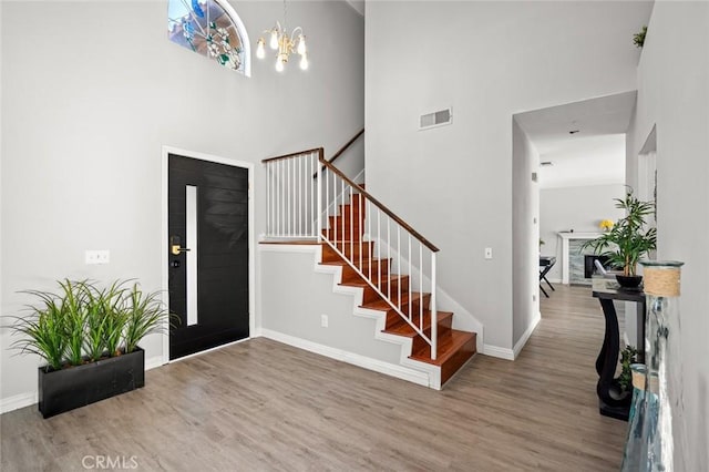 entrance foyer with baseboards, visible vents, stairway, wood finished floors, and a chandelier