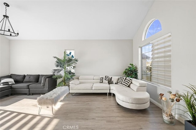 living room with high vaulted ceiling, a notable chandelier, baseboards, and wood finished floors