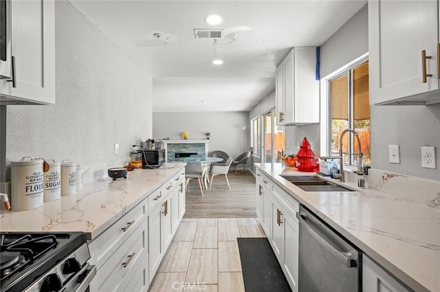 kitchen featuring white cabinets, visible vents, a sink, and stainless steel dishwasher