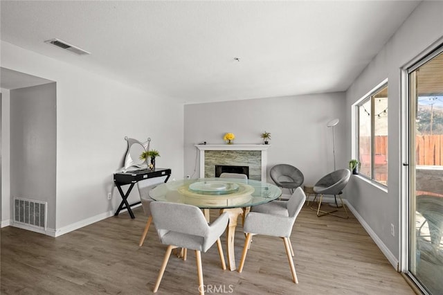 dining area featuring light wood-type flooring, a fireplace, and visible vents