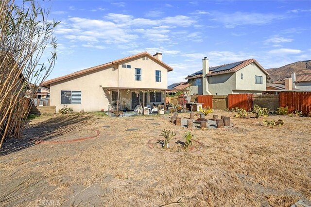 rear view of house featuring solar panels and a patio