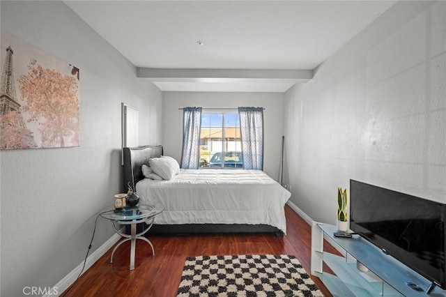 bedroom featuring beamed ceiling, baseboards, and wood finished floors