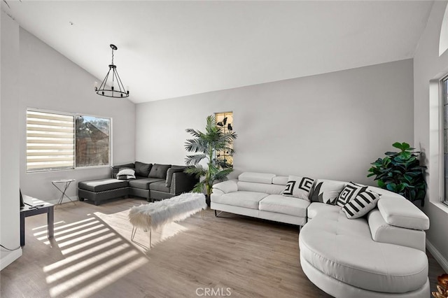 living area with vaulted ceiling, wood finished floors, and an inviting chandelier