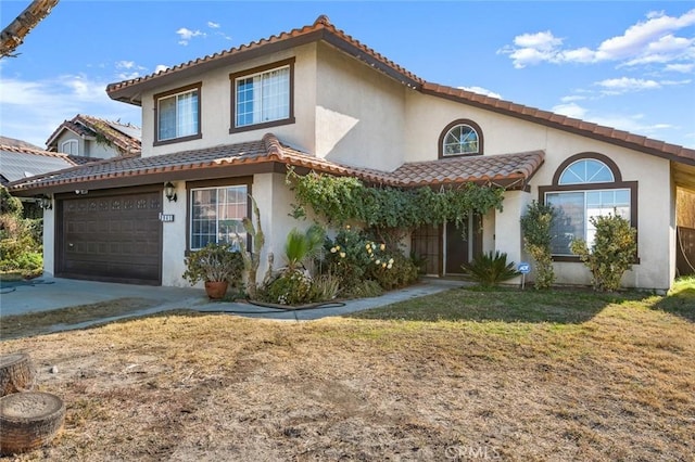 mediterranean / spanish house with a front yard, concrete driveway, a tiled roof, and stucco siding