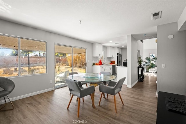 dining area featuring visible vents, baseboards, and wood finished floors