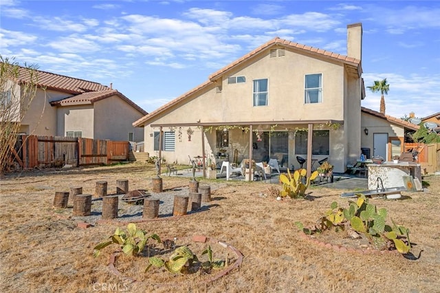 back of house featuring a patio, a fire pit, fence, stucco siding, and a chimney