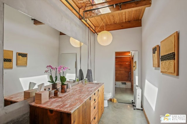 bathroom with radiator heating unit, vanity, toilet, beam ceiling, and concrete flooring