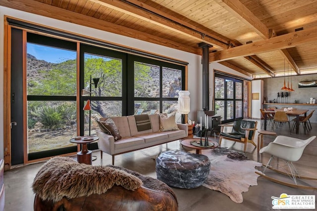 living room featuring wooden ceiling, a wood stove, beamed ceiling, and concrete flooring