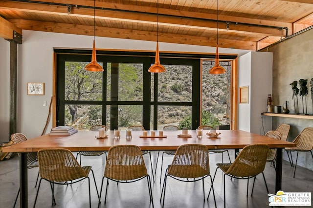 dining area with concrete floors, wooden ceiling, and beam ceiling