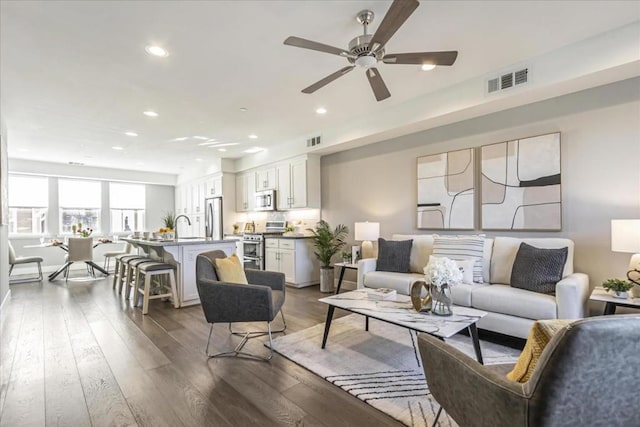 living room featuring ceiling fan, sink, and dark hardwood / wood-style floors