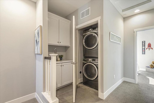 laundry room featuring stacked washer / drying machine and light colored carpet