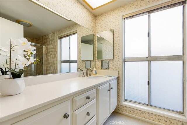 bathroom with a healthy amount of sunlight, a shower with shower door, and vanity