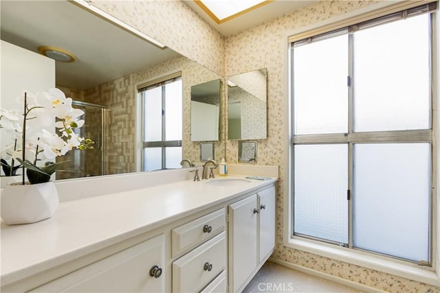 bathroom with wallpapered walls, a shower stall, and vanity