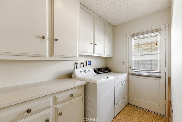 clothes washing area featuring washing machine and dryer, cabinets, and a textured ceiling