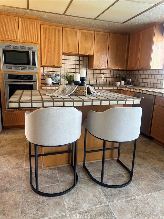 kitchen featuring appliances with stainless steel finishes, tile counters, and tasteful backsplash