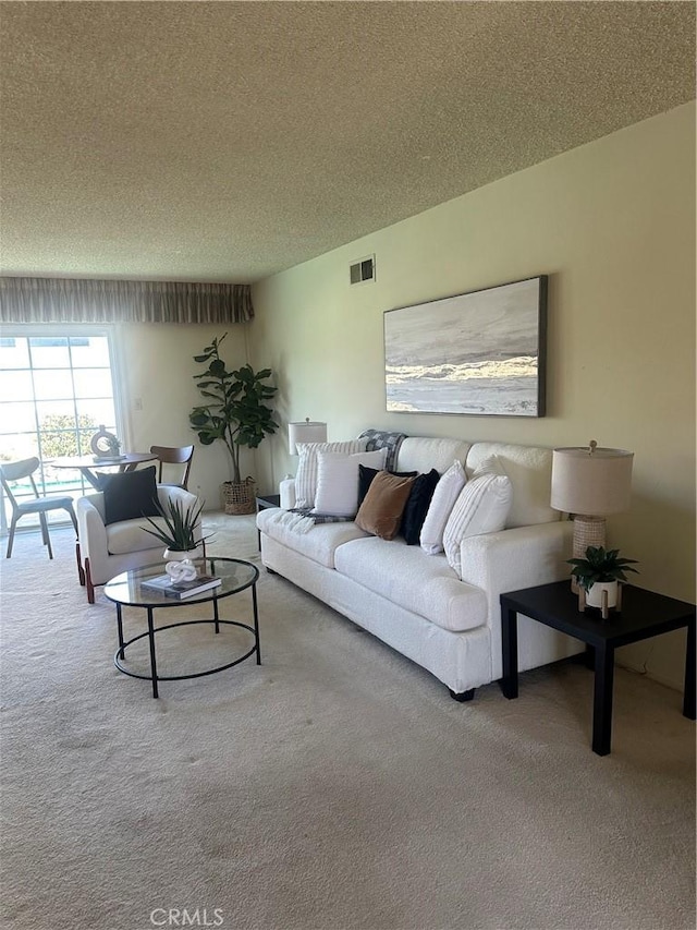 living area with a textured ceiling, carpet flooring, and visible vents