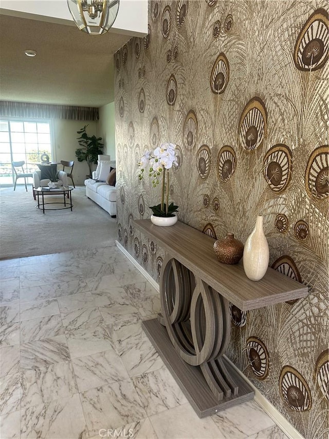 hallway with marble finish floor, baseboards, and wallpapered walls