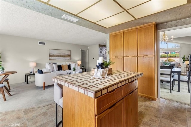 3521 Fern Cir, Seal Beach, CA 90740 - kitchen featuring tile countertops, light carpet, a chandelier, a kitchen island, and open floor plan