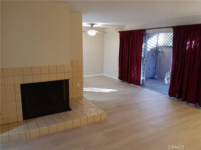 unfurnished living room with ceiling fan, light wood-type flooring, and a fireplace