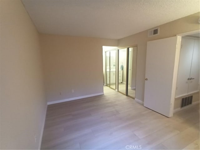 empty room featuring light hardwood / wood-style floors and a textured ceiling