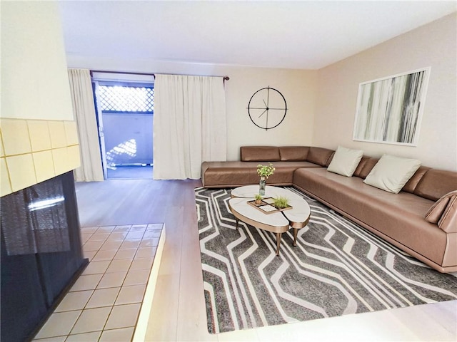 living room with a tiled fireplace and light hardwood / wood-style flooring