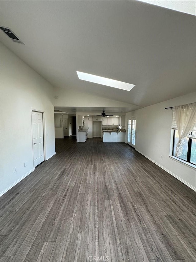 unfurnished living room with ceiling fan, dark hardwood / wood-style flooring, and lofted ceiling with skylight