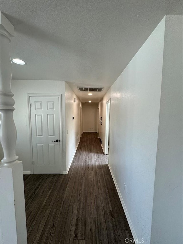 hallway with dark hardwood / wood-style floors and a textured ceiling