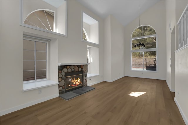 unfurnished living room featuring hardwood / wood-style floors, high vaulted ceiling, and a fireplace