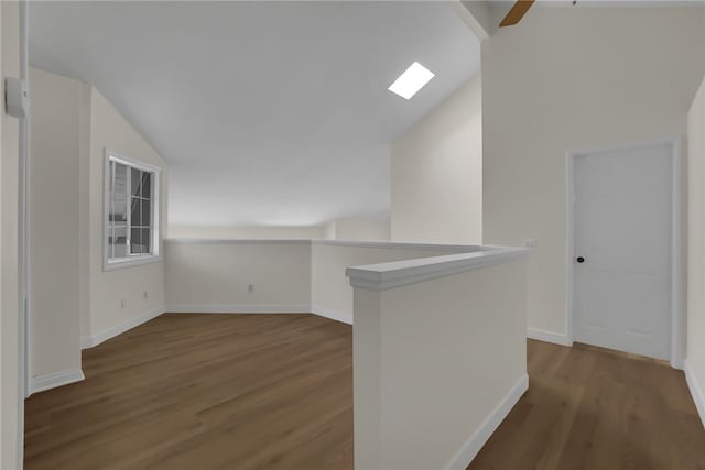 interior space featuring ceiling fan, lofted ceiling with skylight, and wood-type flooring