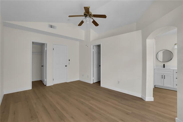 unfurnished bedroom with lofted ceiling, ensuite bathroom, ceiling fan, and light hardwood / wood-style floors