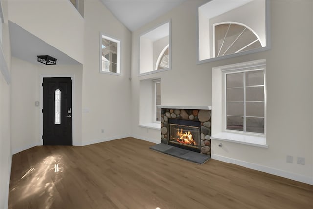 unfurnished living room featuring a high ceiling, a fireplace, and wood-type flooring